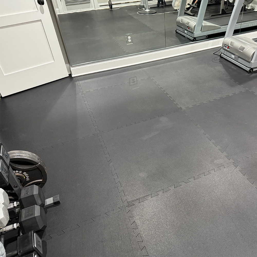 Haseen rubber gym flooring tiles installed in a home gym with dumbbells and treadmill — gym flooring price in Pakistan